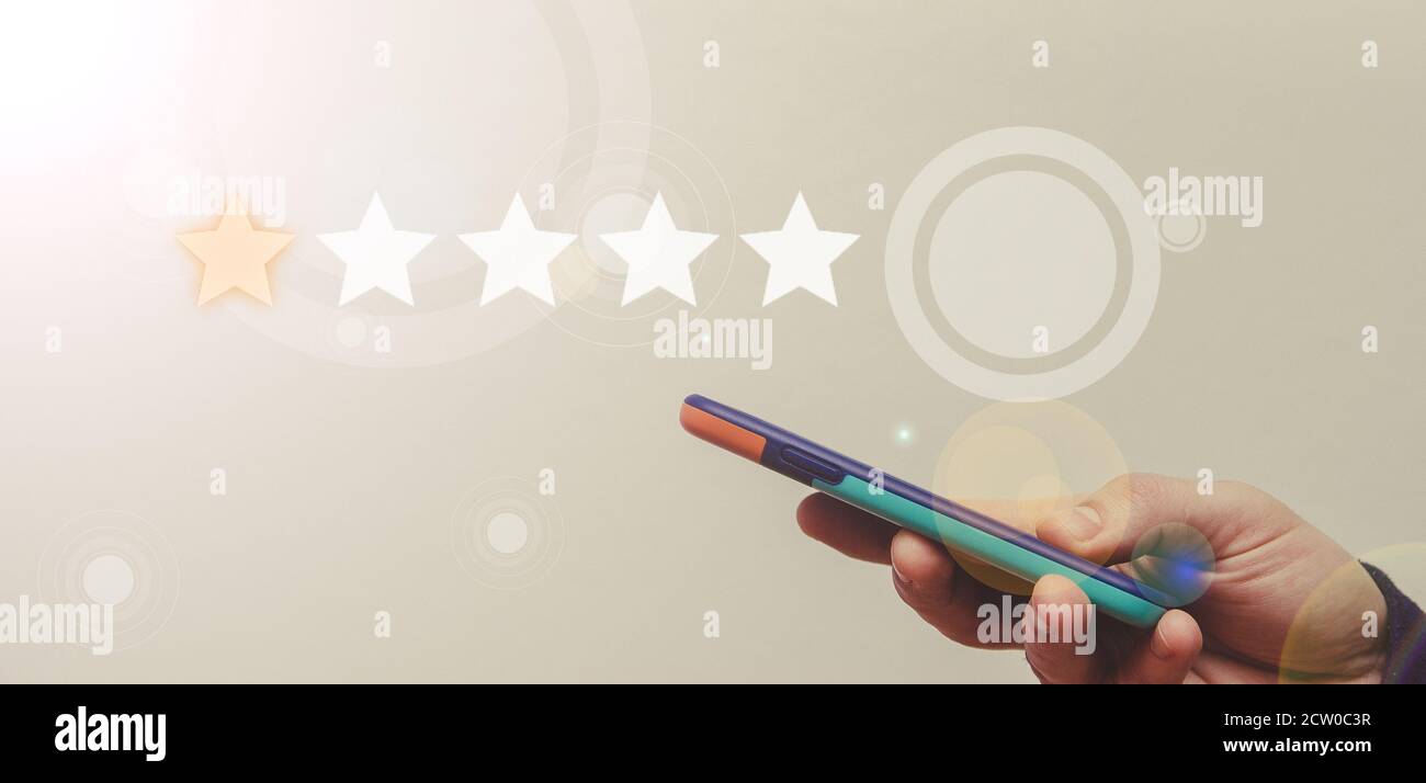 Close-up of a hand with a smartphone. Five star feedback to give excellent job concept. Stock Photo