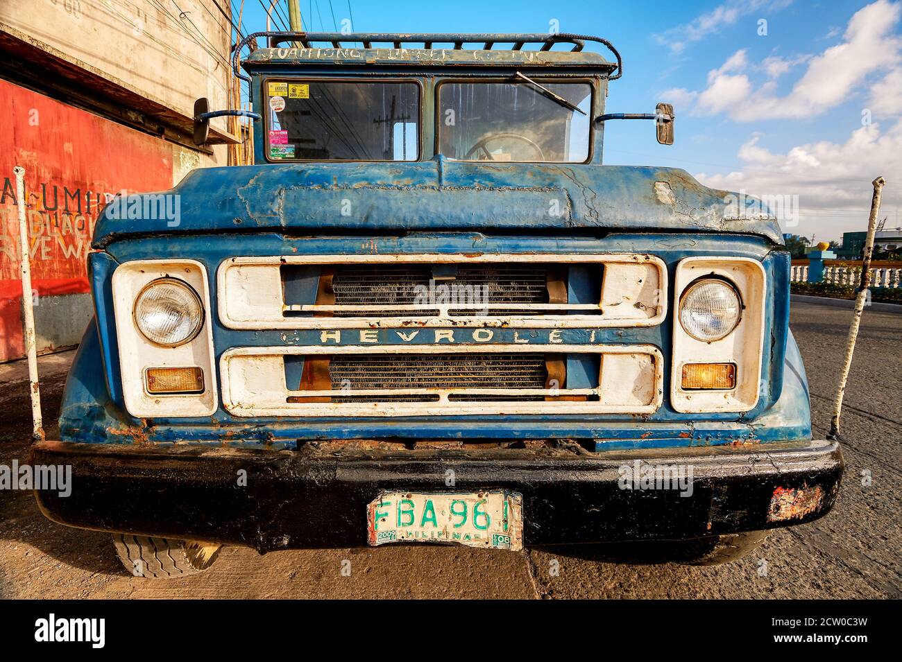 Front low angle view of an old blue colored rusty dirty Chevrolet cargo truck parked along a road in Iloilo City, Philippines Stock Photo
