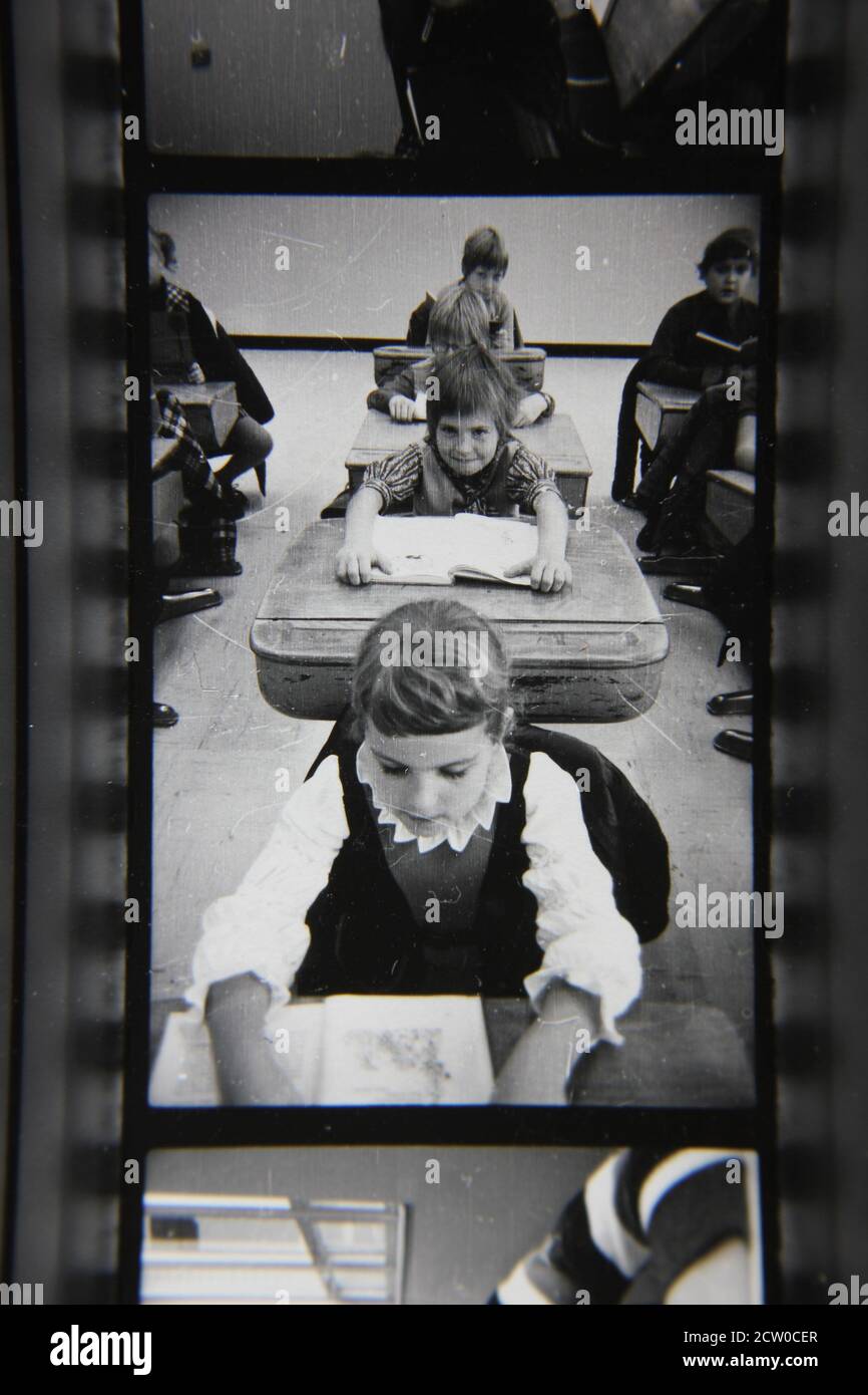 Fine 1970s vintage black and white photography of grade school students sitting in their desks and following the daily lessons. Stock Photo
