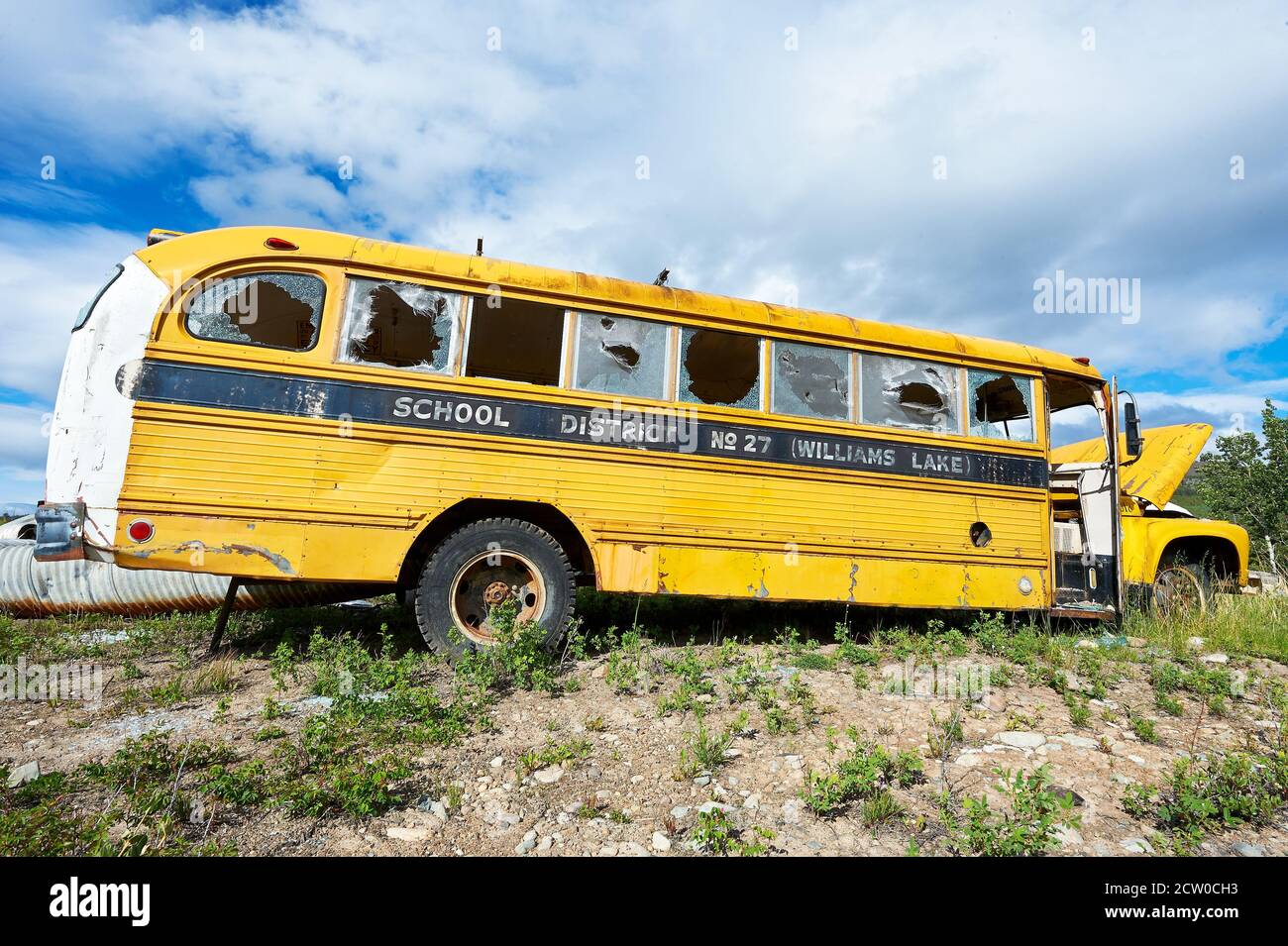 Old yellow vandalized american school bus with broken glass windows on a government dump site near Chilco Lake, British Vancouver, Canada Stock Photo