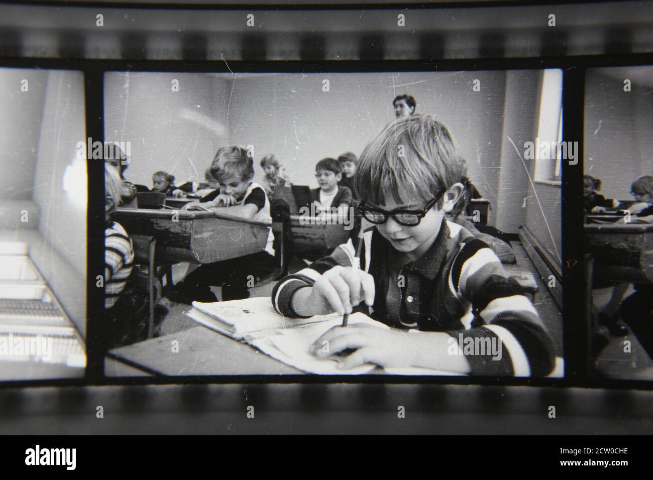 Fine 1970s vintage black and white photography of grade school students sitting in their desks and following the daily lessons. Stock Photo