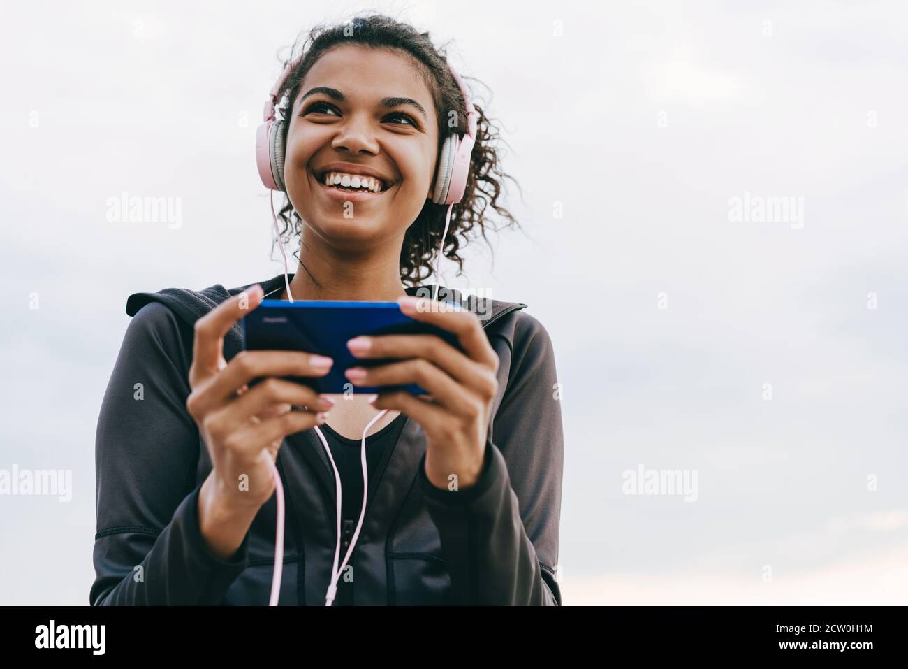 Image of smiling african american woman using cellphone and headphones ...
