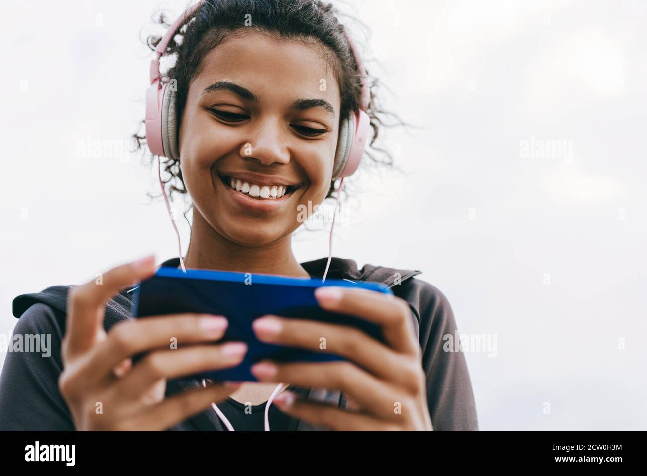 Image of smiling african american woman using cellphone and headphones ...