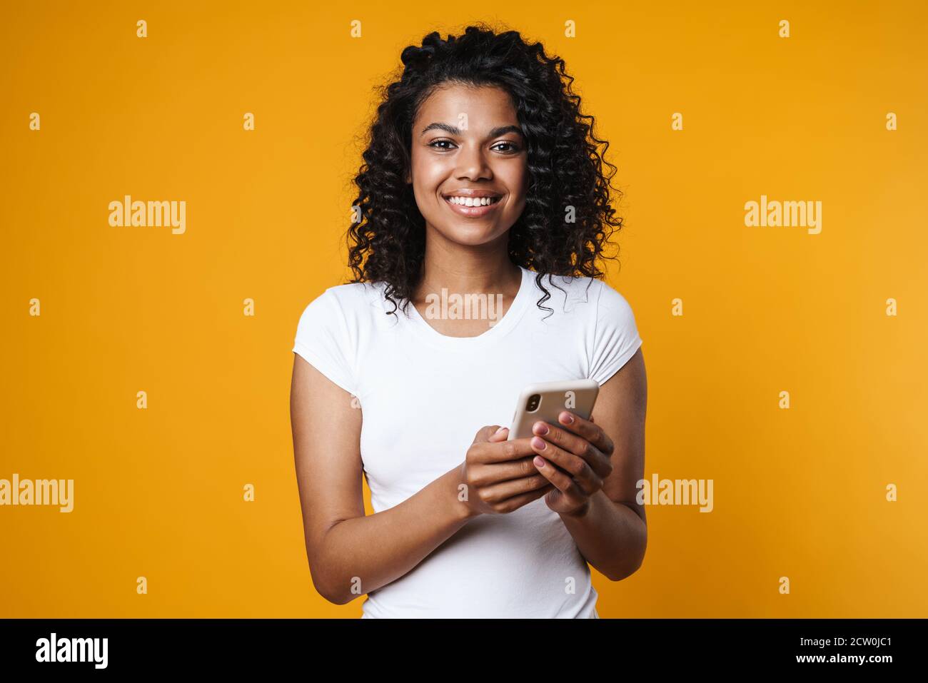 Image of cheerful african american woman smiling and using cellphone ...