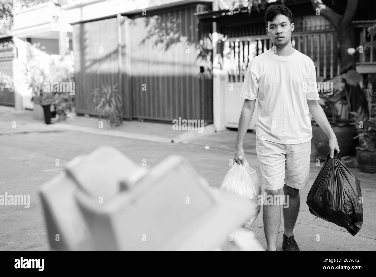 Young Asian man taking out the garbage at home Stock Photo