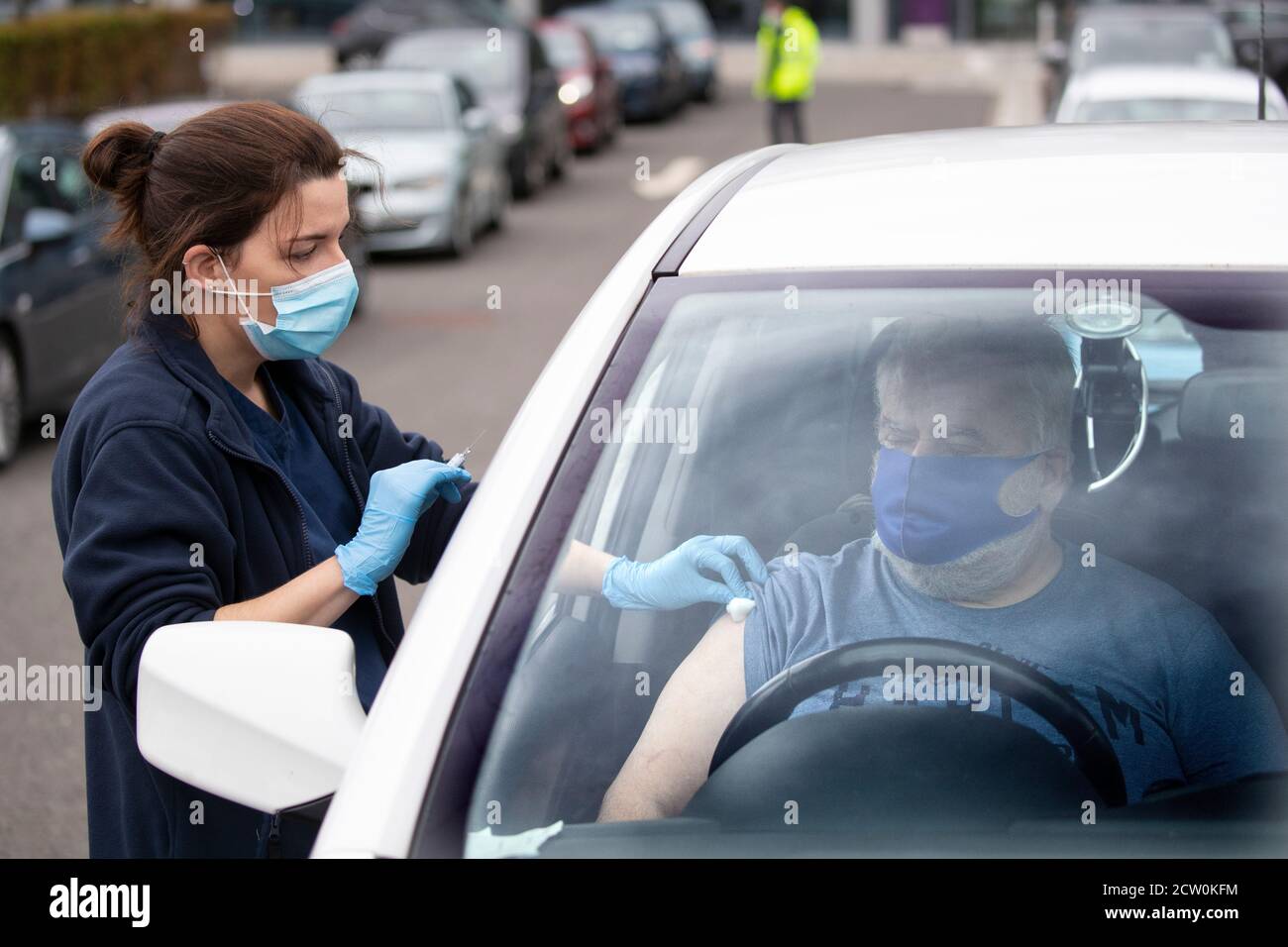 A member of the public receives a flu vaccine sat in their car at one of the new the drive-thru flu clinics at Little France, Edinburgh. Stock Photo