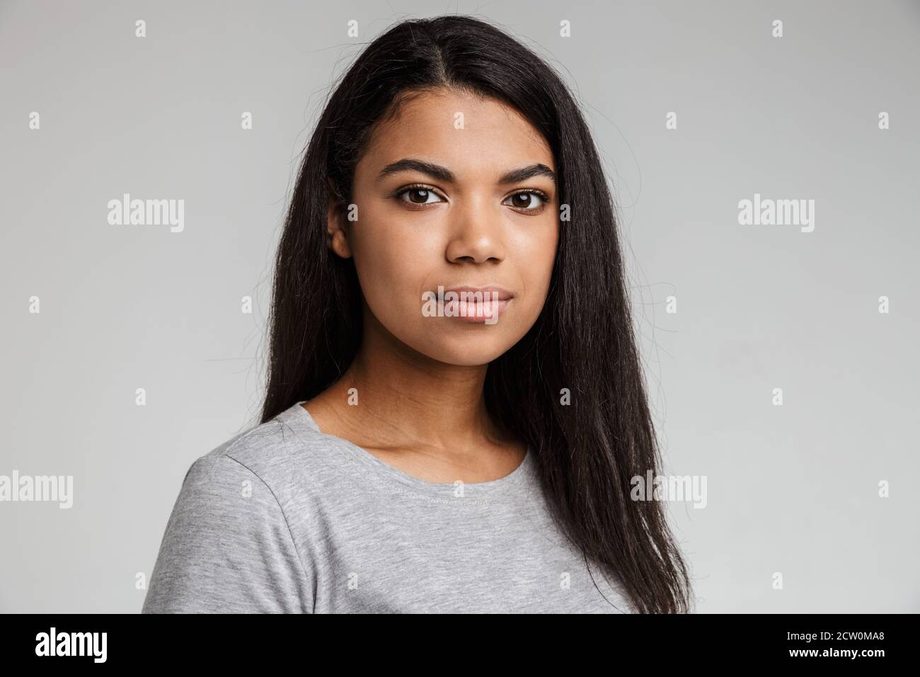 Close up portrait of a beautiful african girl smiling on isolated gray ...