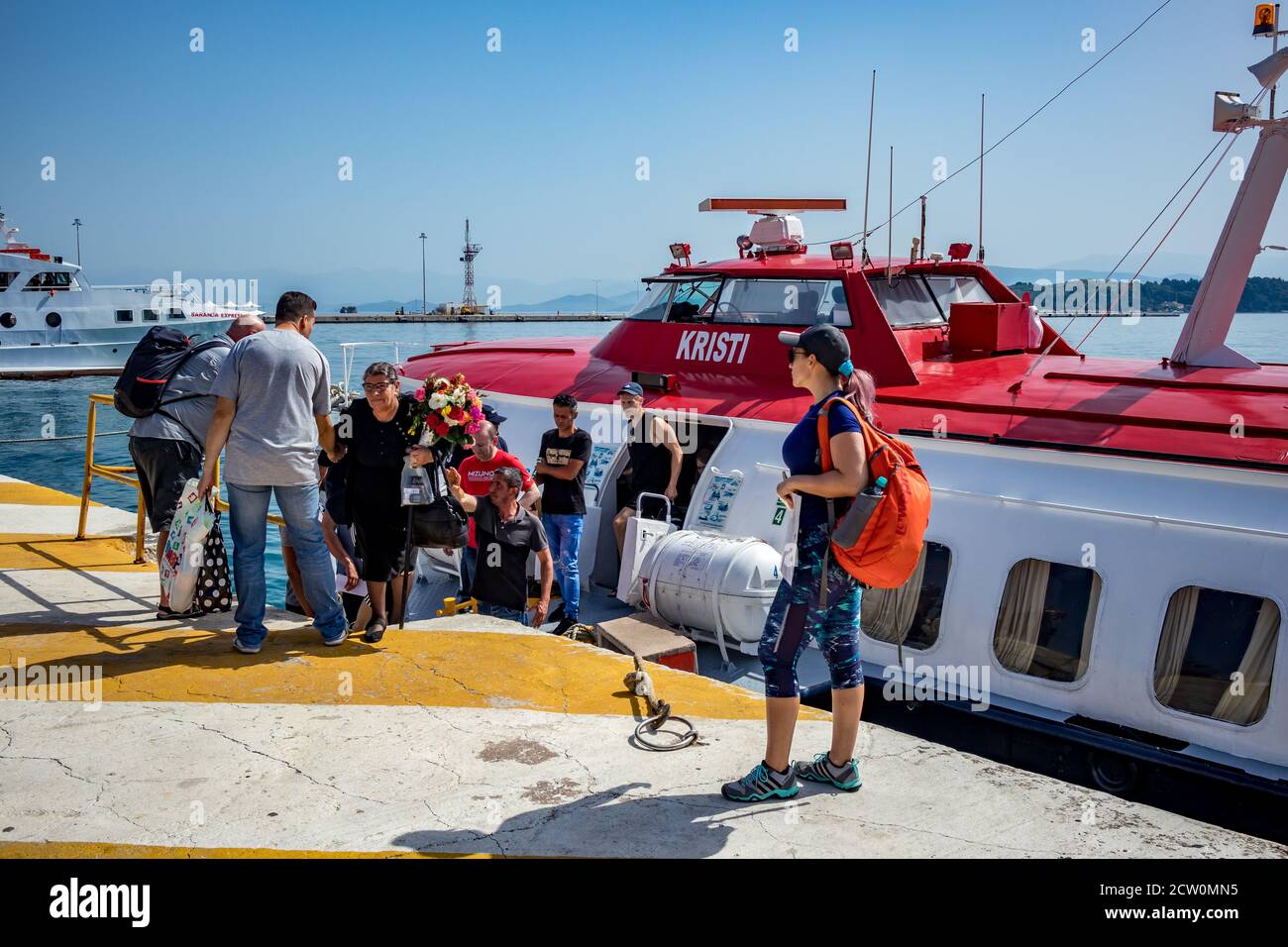 Corfu, Greece - July 20, 2019: Tourists get help getting out of the speed boat ferry coming from Saranda, Albania. Kerkira marina with the blue waters of Ionian Sea. Stock Photo