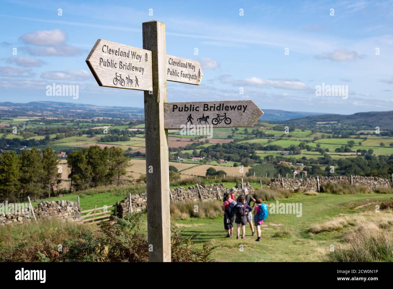 Walkers on the Cleveland Way footpath on the edge of the North York Moors heading towards Huthwaite Green, North Yorkshire, England, UK Stock Photo