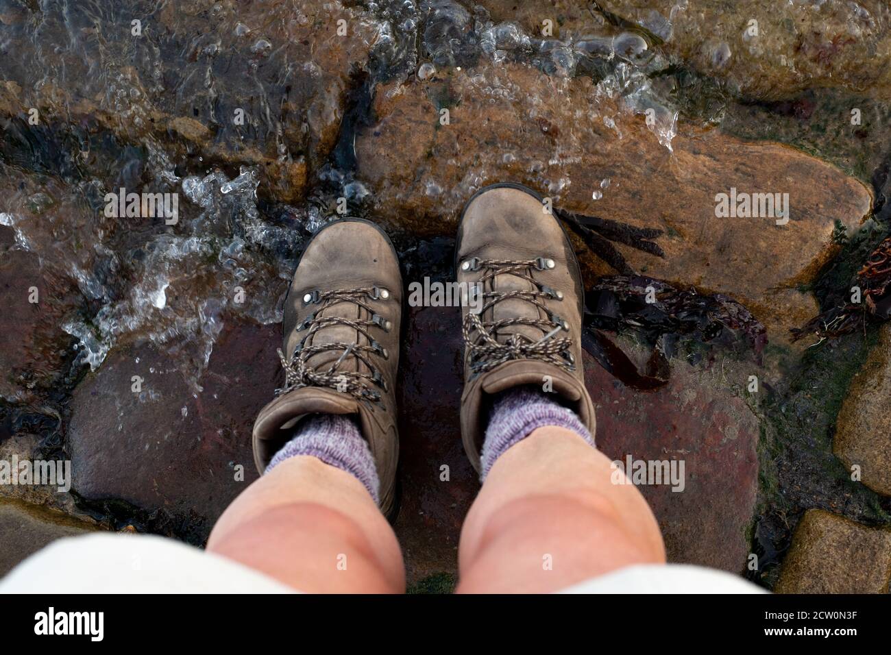 Coast to coast walk, UK - customary dipping walking boots in the North sea at the end of the walk, Robin Hoods Bay, North Yorkshire, England, UK Stock Photo