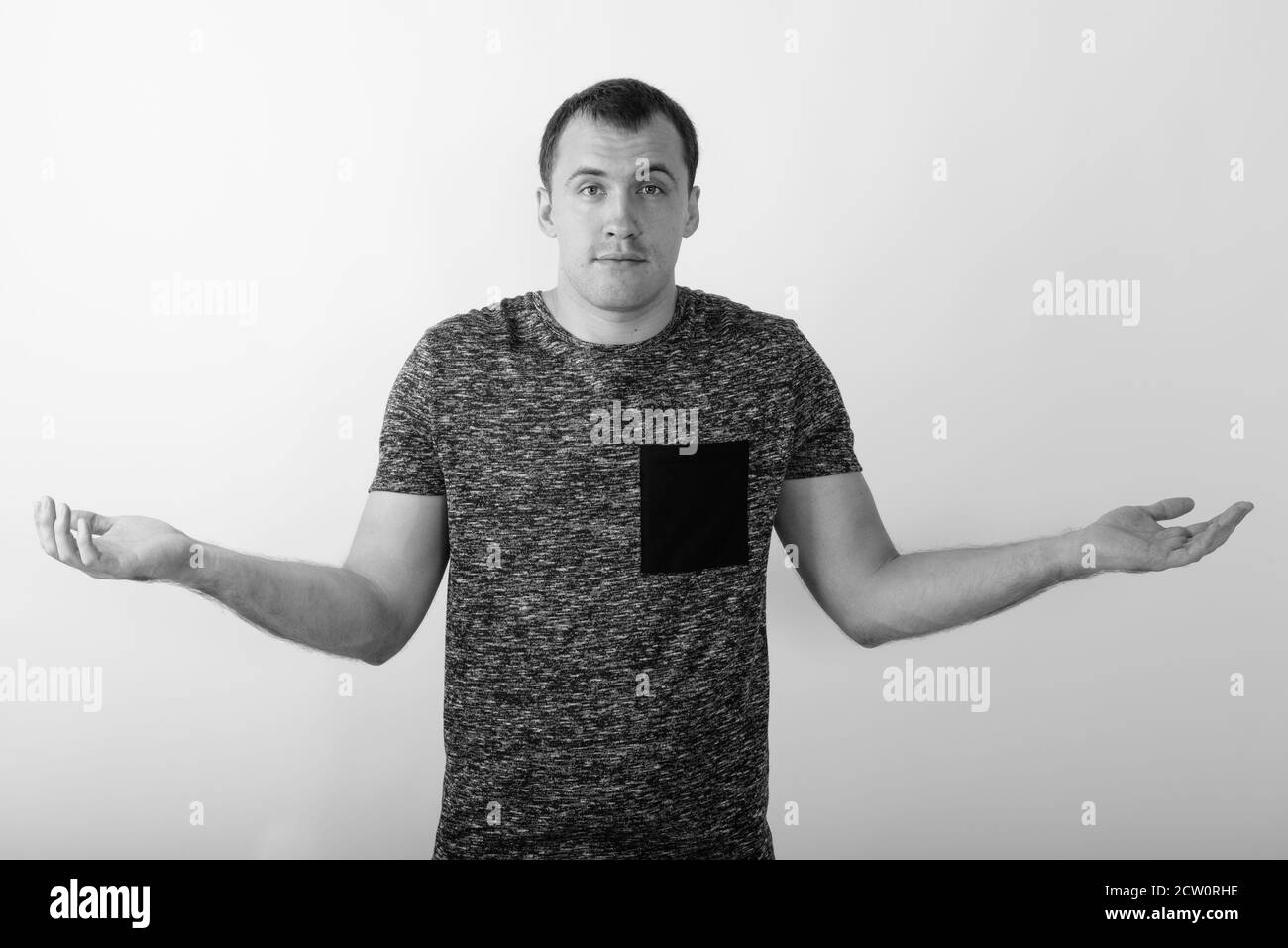 Studio shot of young muscular man looking confused against white background Stock Photo