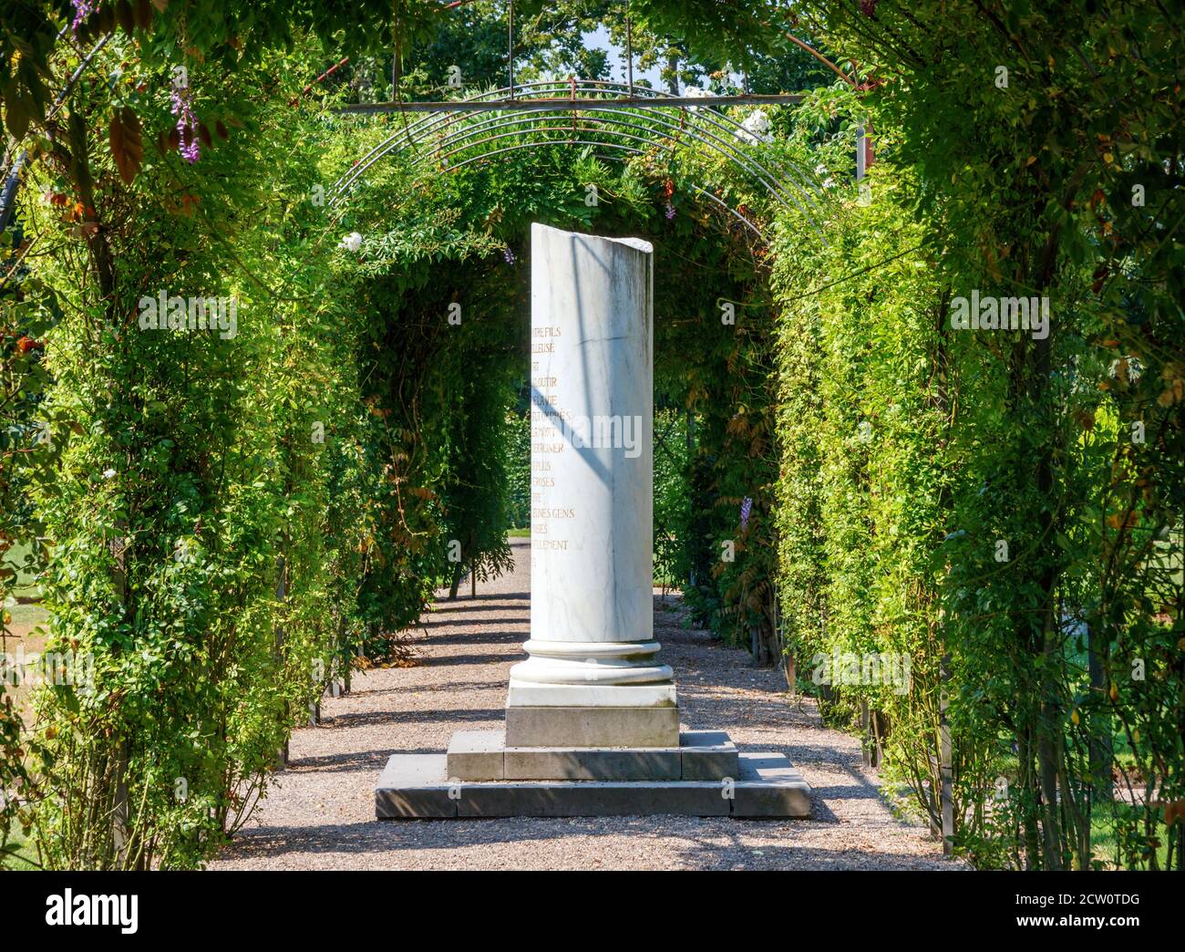 Old column surrounded by flora on a sunny day. Castle De Haar, Haarzuilens, Utrecht, The Netherlands. Stock Photo