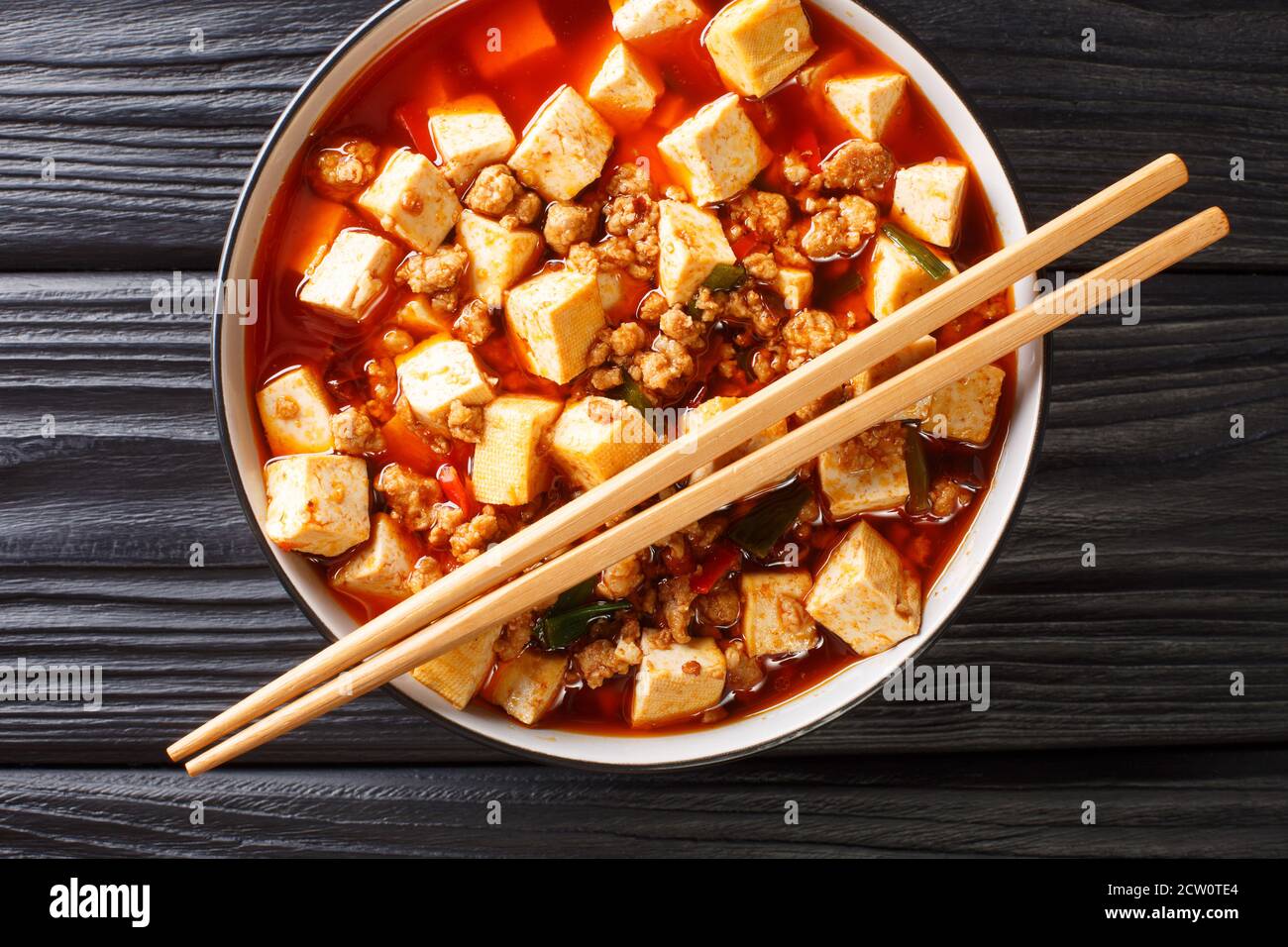 Tender mapo tofu cooked in an aromatic and spicy sauce, accompanied by minced meat closeup in the plate on the table. Horizontal top view from above Stock Photo