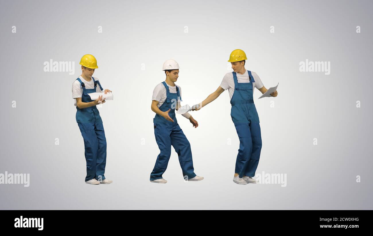 Three young construction workers in hardhats passing on document Stock Photo