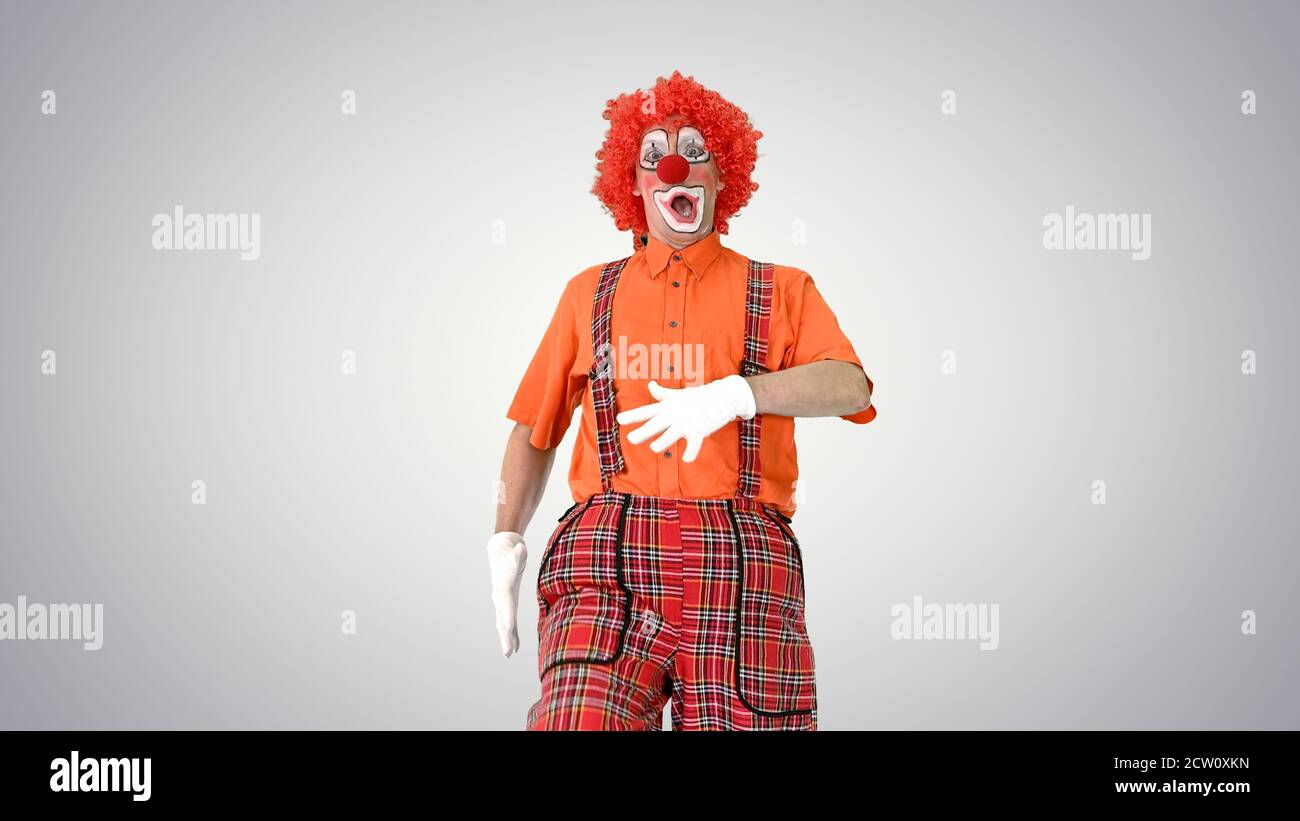 Clown walking in a comic way towards the camera on gradient back Stock Photo