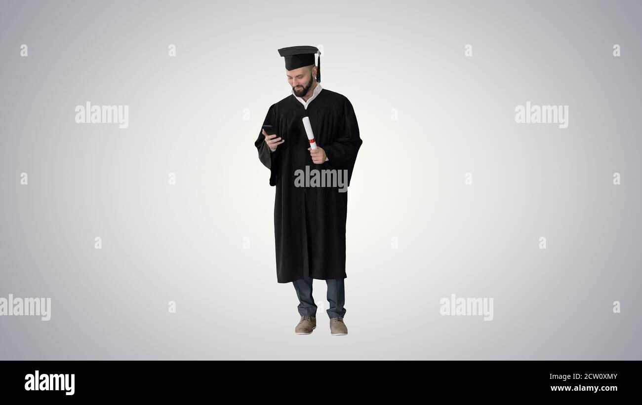 Graduate student texting on the phone on gradient background. Stock Photo