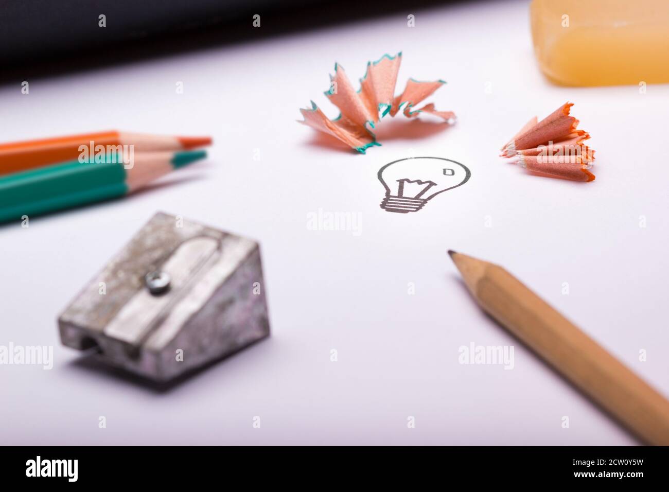 A light bulb with sharpener waste, eraser and colour pencils as a