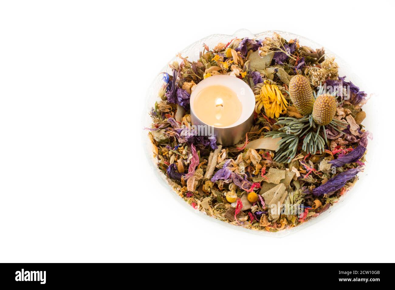 Glass bowl with potpourri of dried flowers, candle and two pinecones