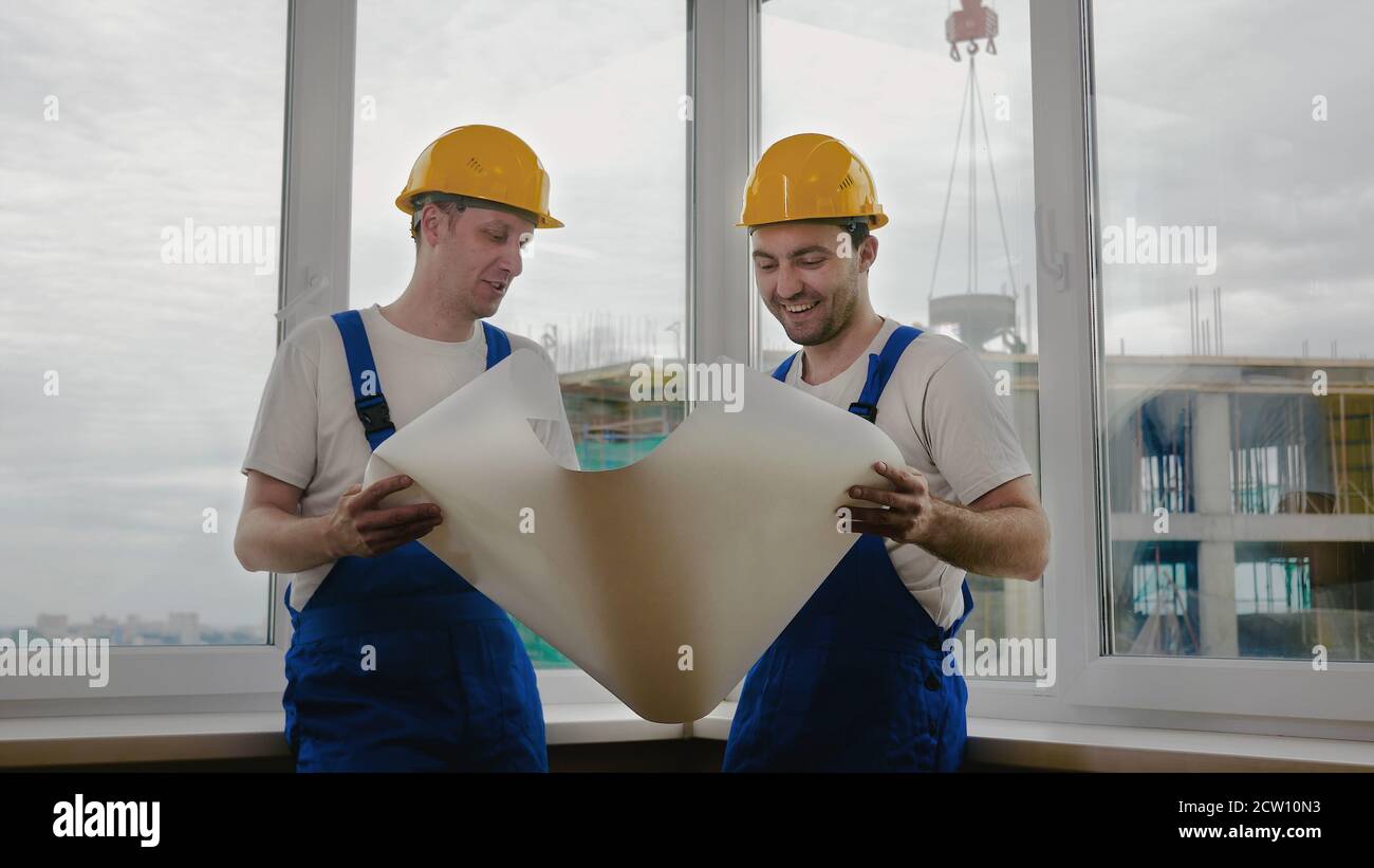 Workers in helmets looking at drawings, repairs Stock Photo