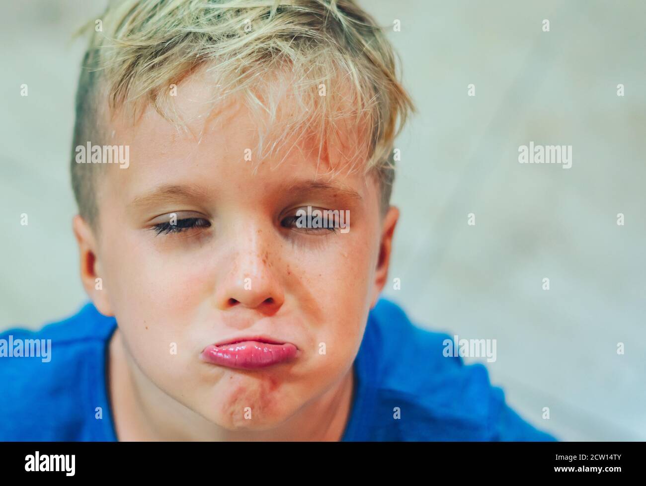 Closeup portrait boy mischievous cute blond close blue eyes, stuck out