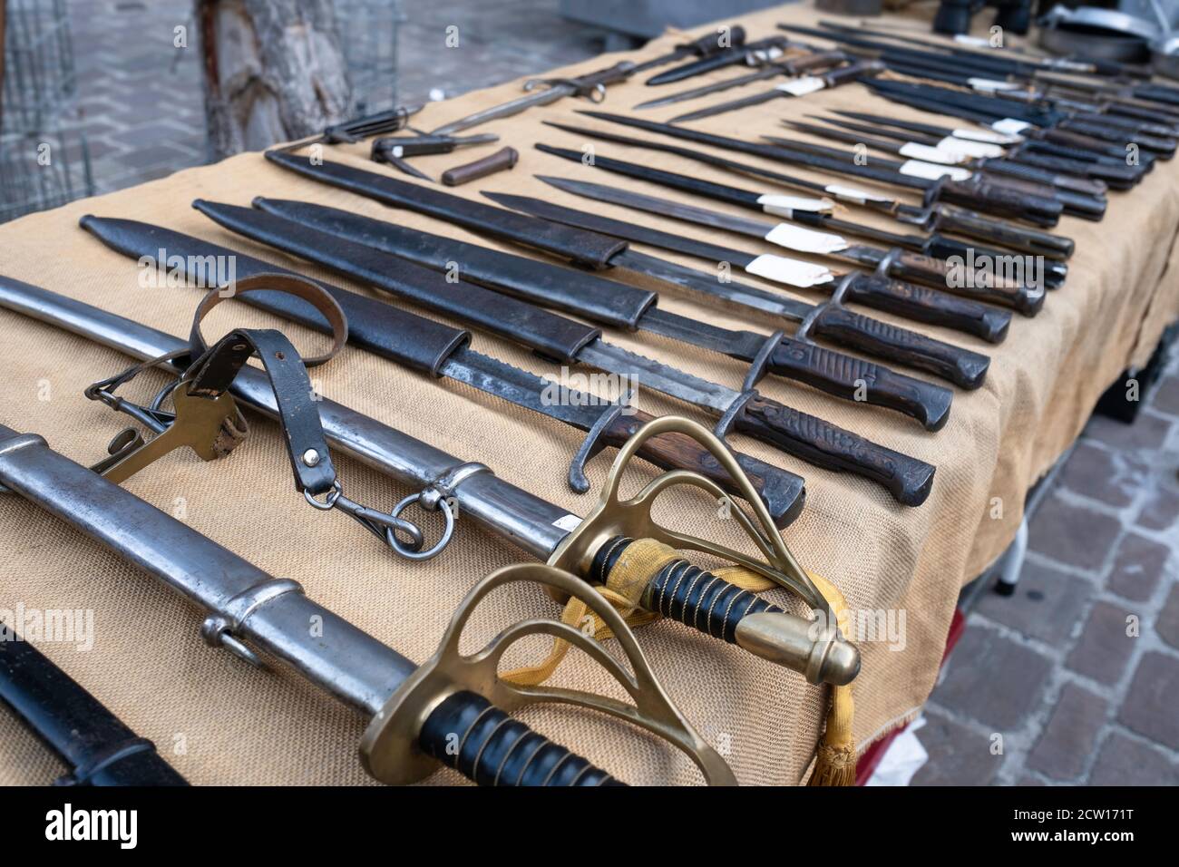 All kinds of swords with scabbards in different sizes displayed on a table for sale on an antique market in Tongeren, Belgium Stock Photo