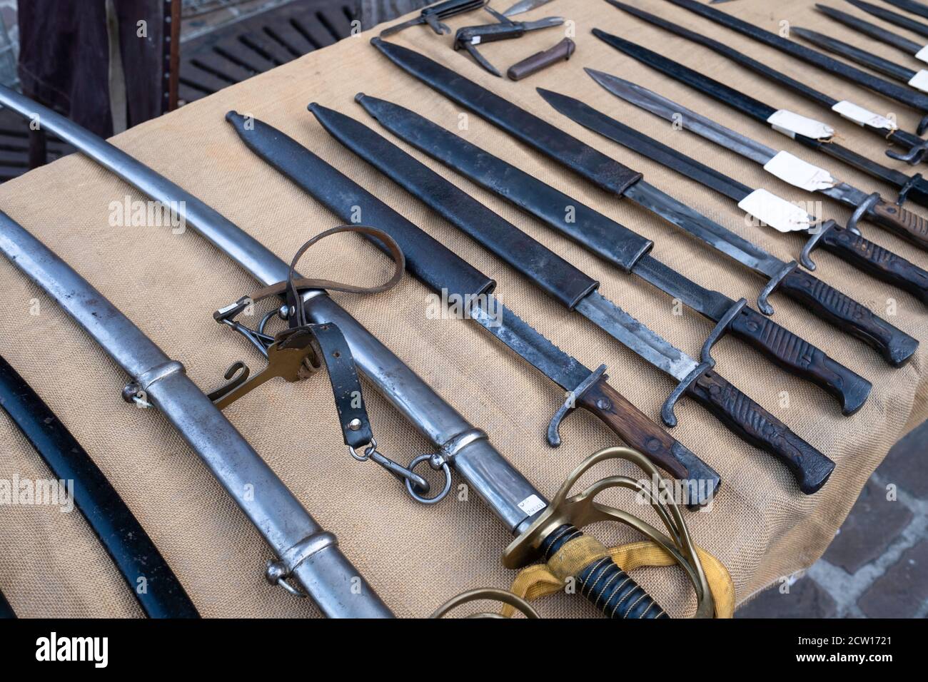 All kinds of swords with scabbards in different sizes displayed on a table for sale on an antique market in Tongeren, Belgium Stock Photo