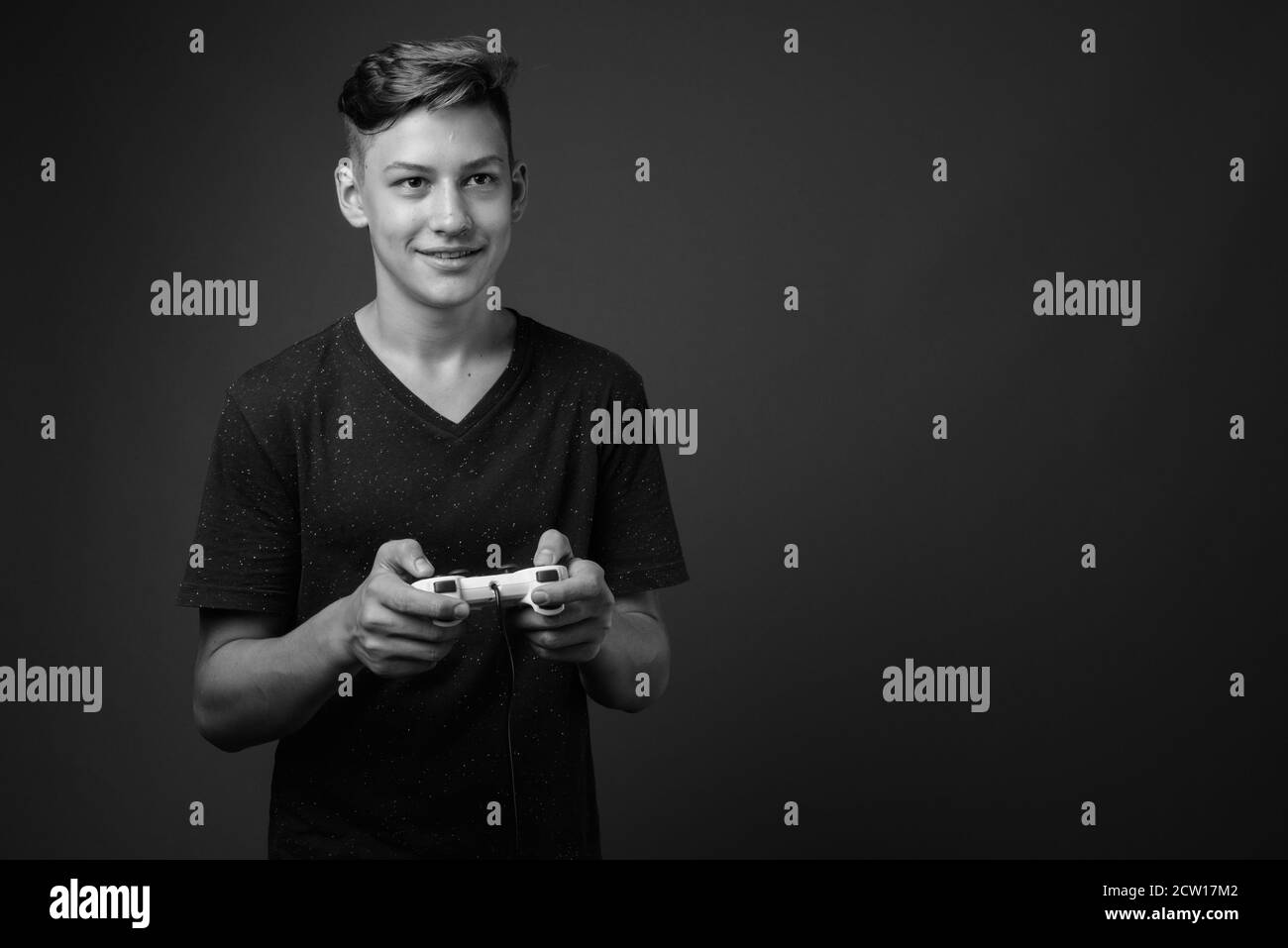 Studio shot of young handsome teenage boy against gray background Stock Photo