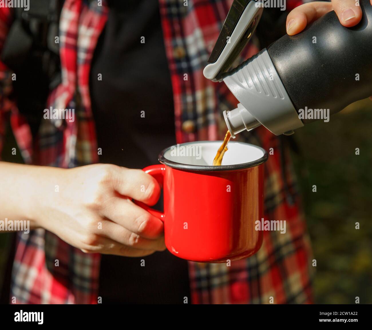 https://c8.alamy.com/comp/2CW1A22/tourist-hands-pour-coffee-from-a-thermos-into-a-metal-red-cup-2CW1A22.jpg