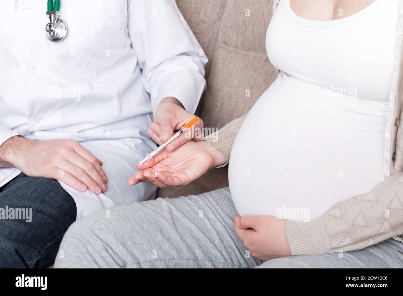 Doctor is giving syringe of insulin injection to his pregnant patient
