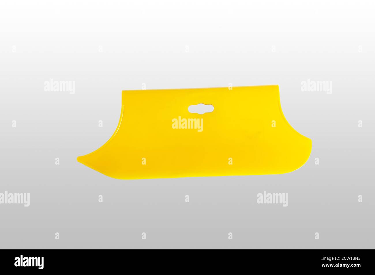 Yellow plastic spatula for wallpaper. Close-up. Isolated on light gray background. Stock Photo