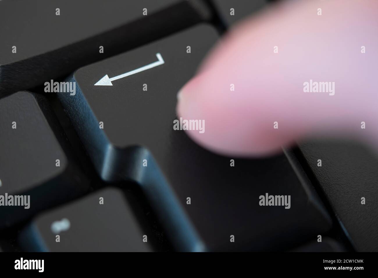 A man's finger hitting the return (enter) key on a computer keyboard. Concept: enter, ok, okay, return, go ahead, permission, technology, computing Stock Photo