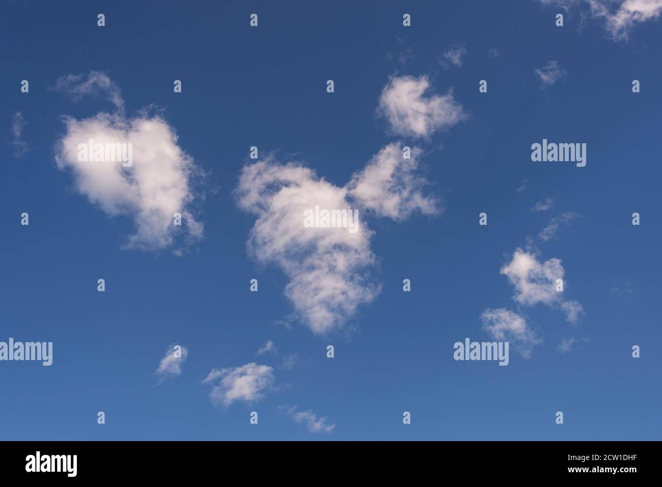 small white fluffy clouds against a blue sky Stock Photo