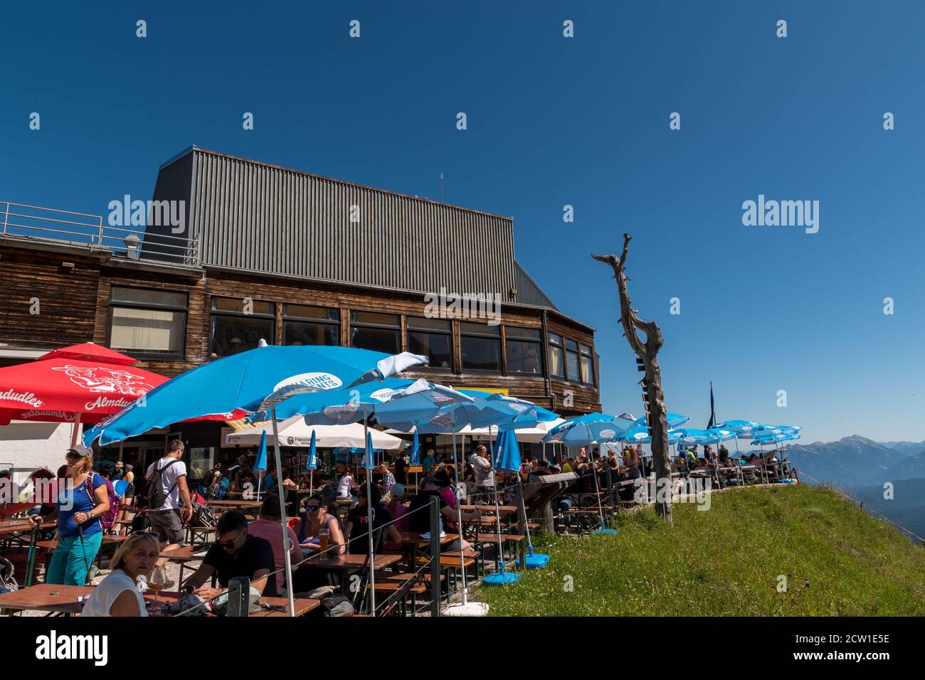 Tourists sitting at the mountain station from the mountain Alpspitze cable car and drink and eat. Stock Photo