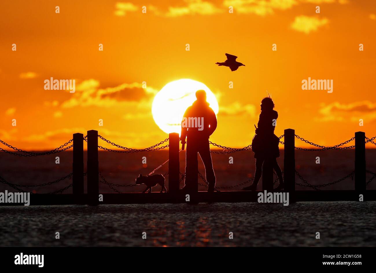 People are seen at Marine Lake as the sun sets over the Bristol Channel, Weston-super-Mare, Britain, September 26, 2020. REUTERS/Peter Cziborra Stock Photo