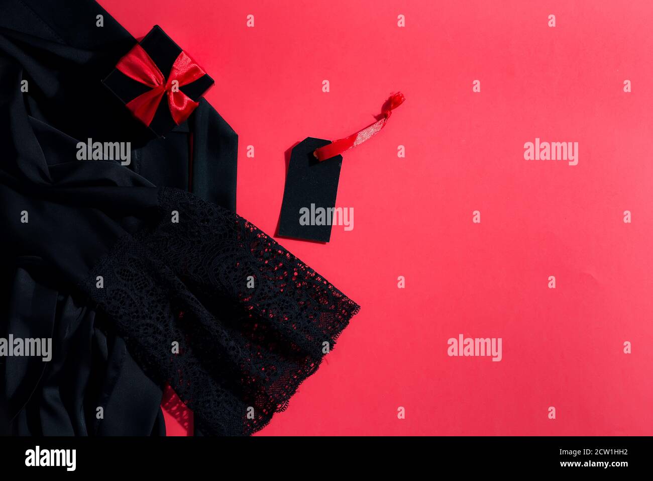 Purchased things - black new woman's clothes, present box and price tag on light coral background, copy space. Top view. Black Friday Sale concept. Stock Photo