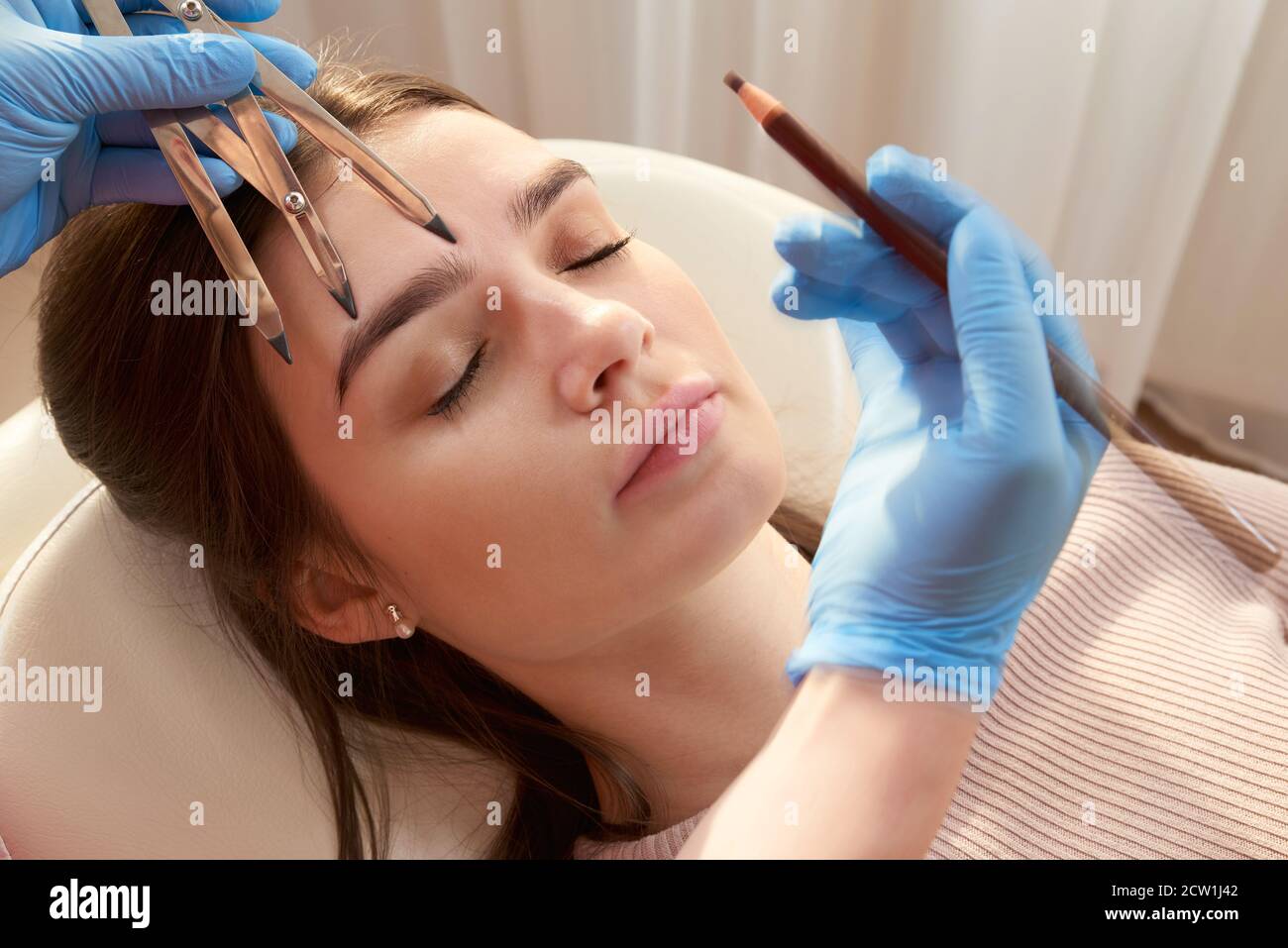 Cosmetologist measures the proportions of the eyebrows with the ruler ...