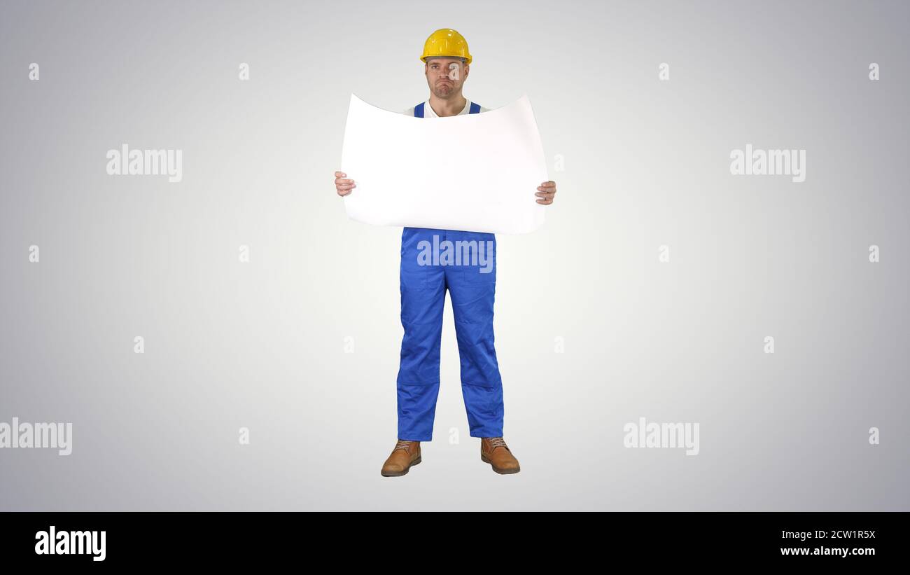 Construction worker checking blueprints on site on gradient back Stock Photo