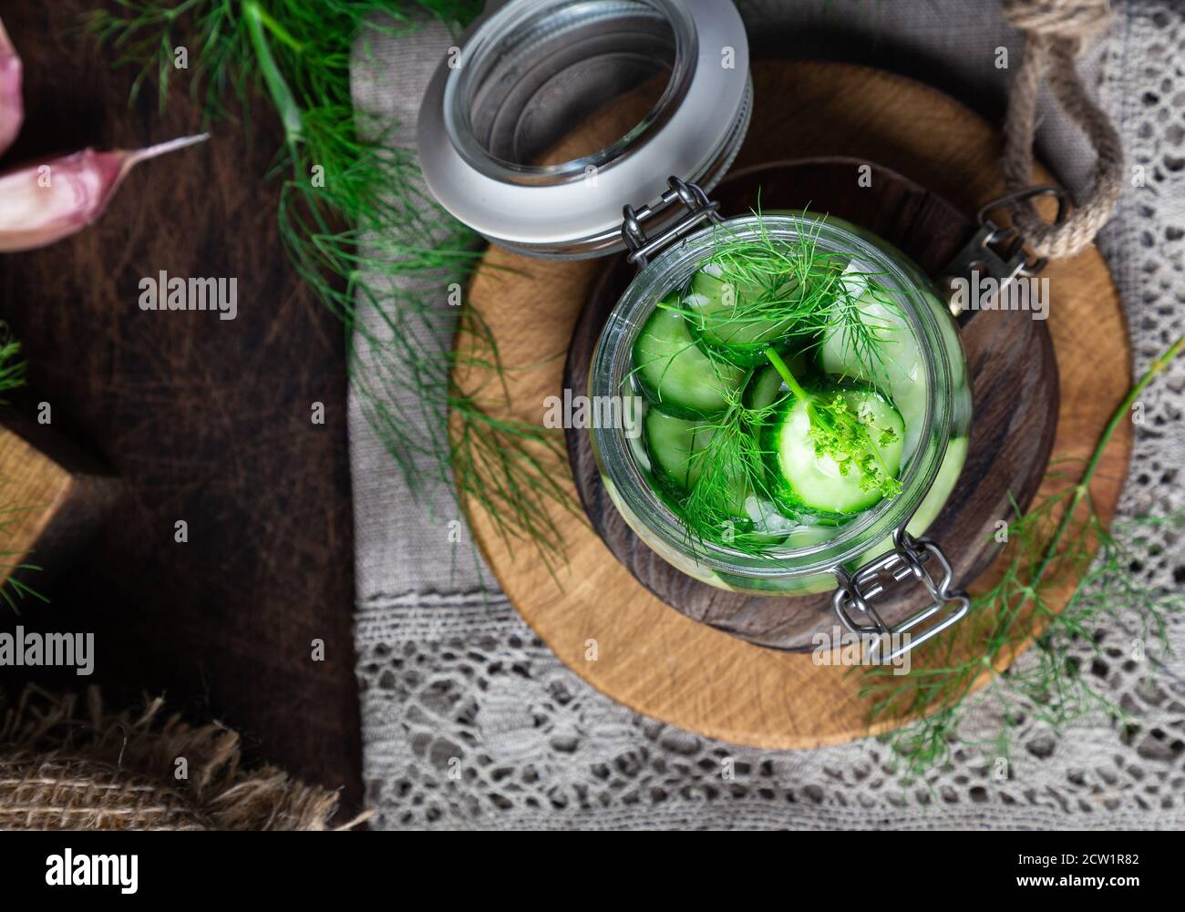 Preparation for pickling cucumbers. Homemade cucumbers cutted into slices with dill and garlic on rustic wooden background. Harvesting vegetables for Stock Photo