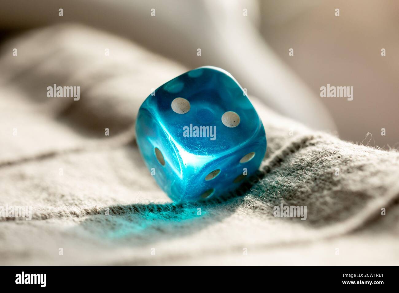 A Blue Dice refracting sunlight Stock Photo