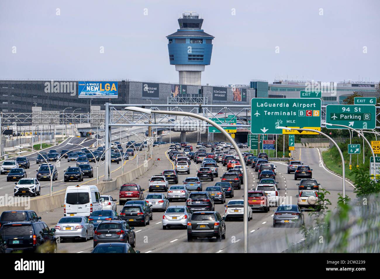 Traffic car on the highway going to LaGuardia Airport. Air traffic Control Tower seen above terminals Stock Photo