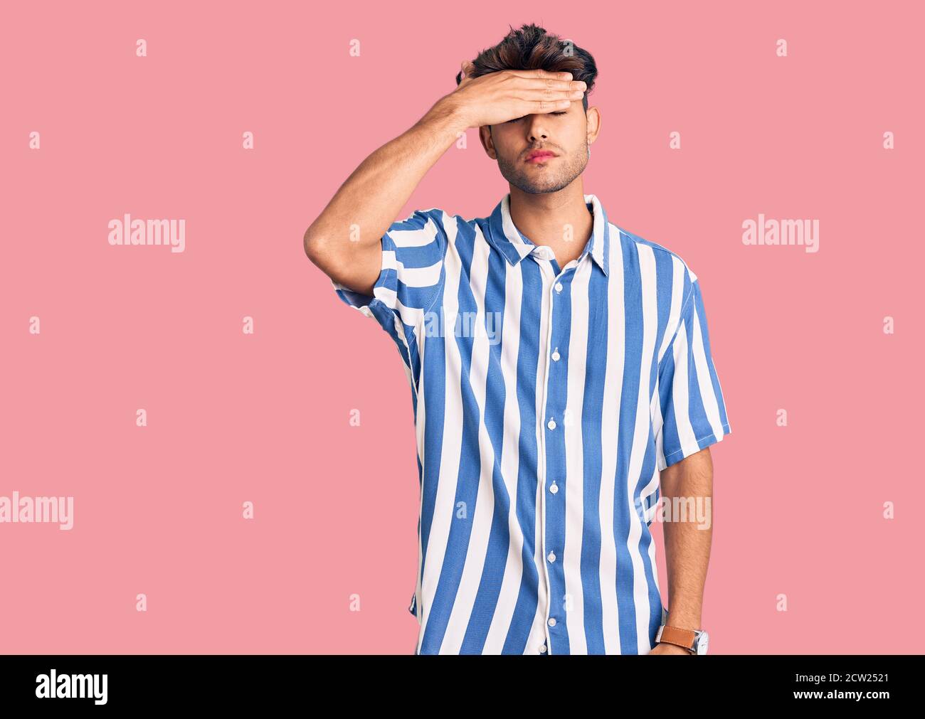 Young hispanic man wearing casual clothes covering eyes with hand ...