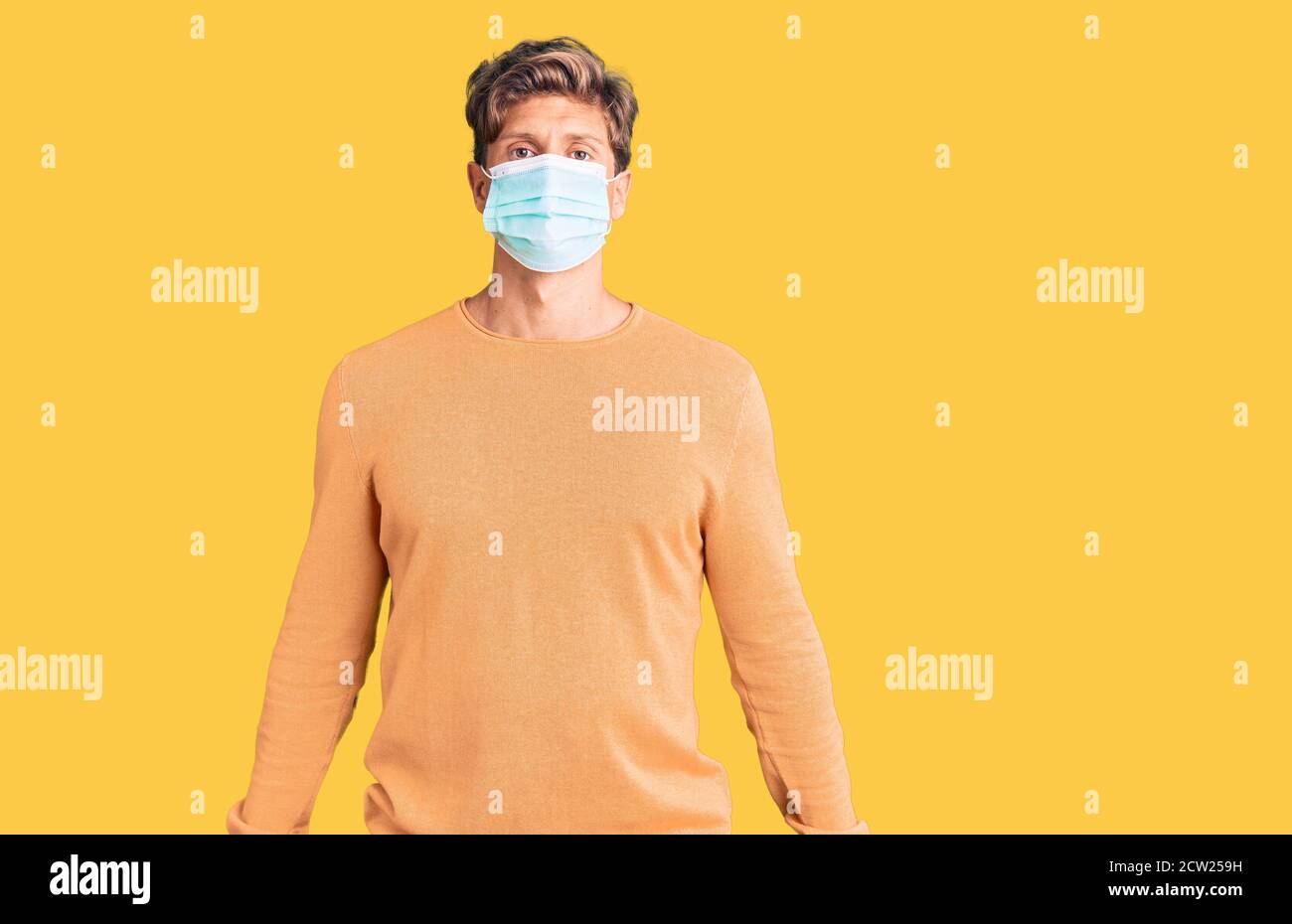 Young handsome man wearing medical mask with serious expression on face ...