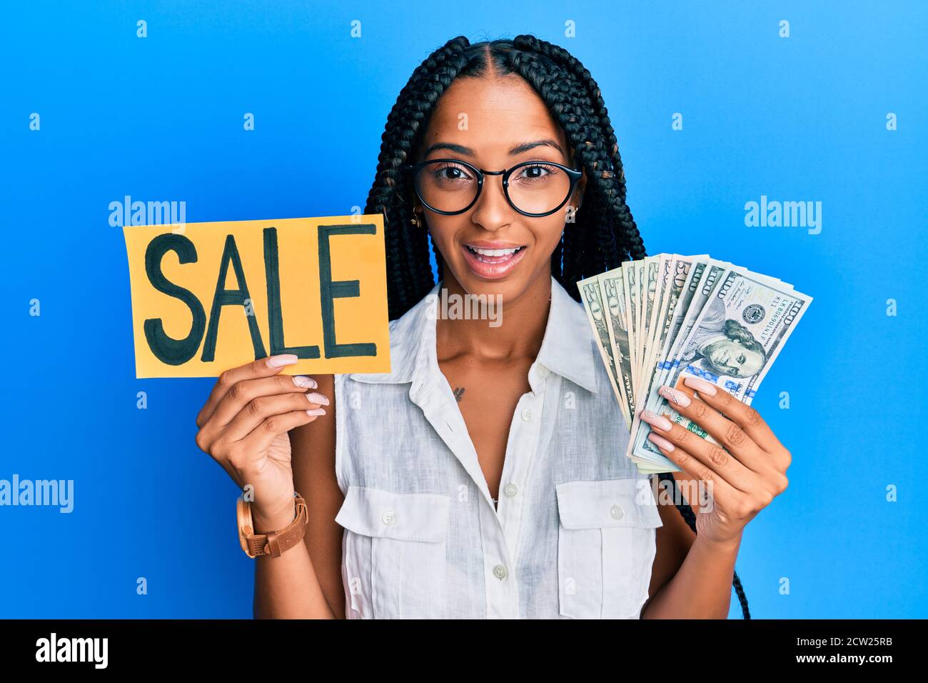 Beautiful hispanic woman holding sale banner and dollars celebrating ...