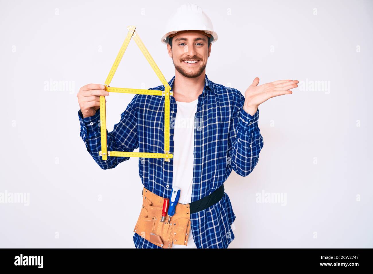 Young handsome man wearing architect hardhat holding build project ...