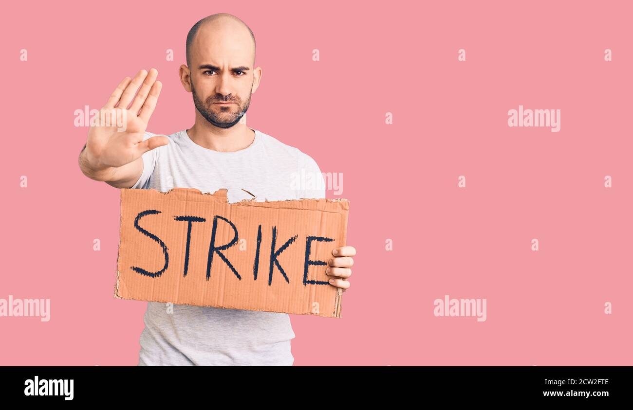 Strike Sign Man Young handsome man holding strike banner with open hand doing stop sign ...