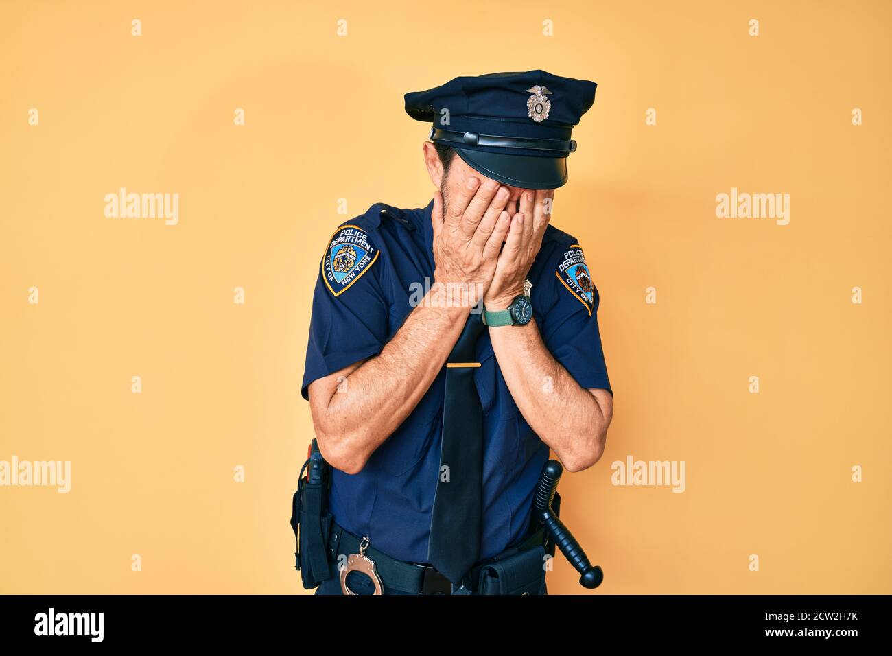 Middle age hispanic man wearing police uniform with sad expression covering face with hands while crying. depression concept. Stock Photo