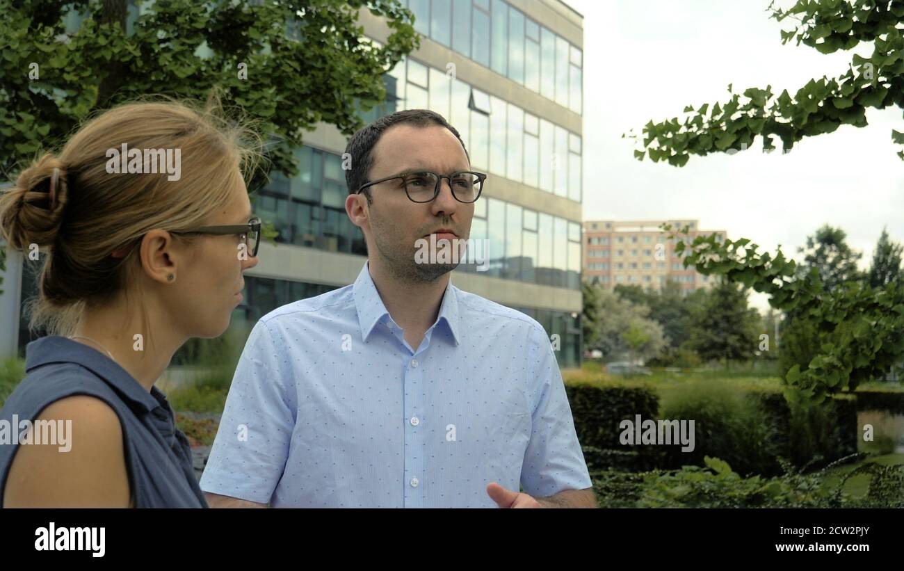 Business man and woman talking standing near office building. Ma Stock Photo
