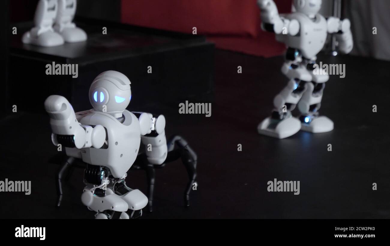 Humanoid robots with colourful illumination dancing. Stock Photo