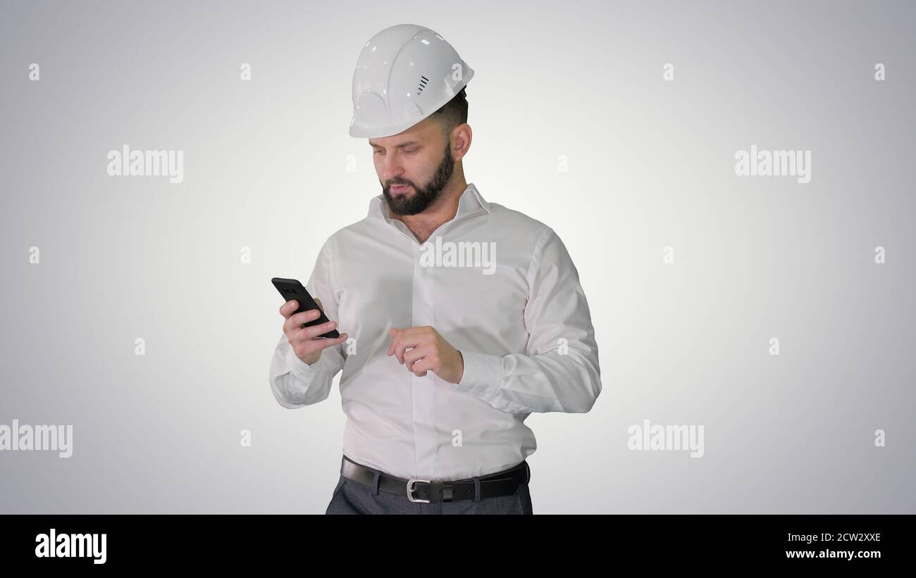 Engineer walking and using smartphone on gradient background. Stock Photo