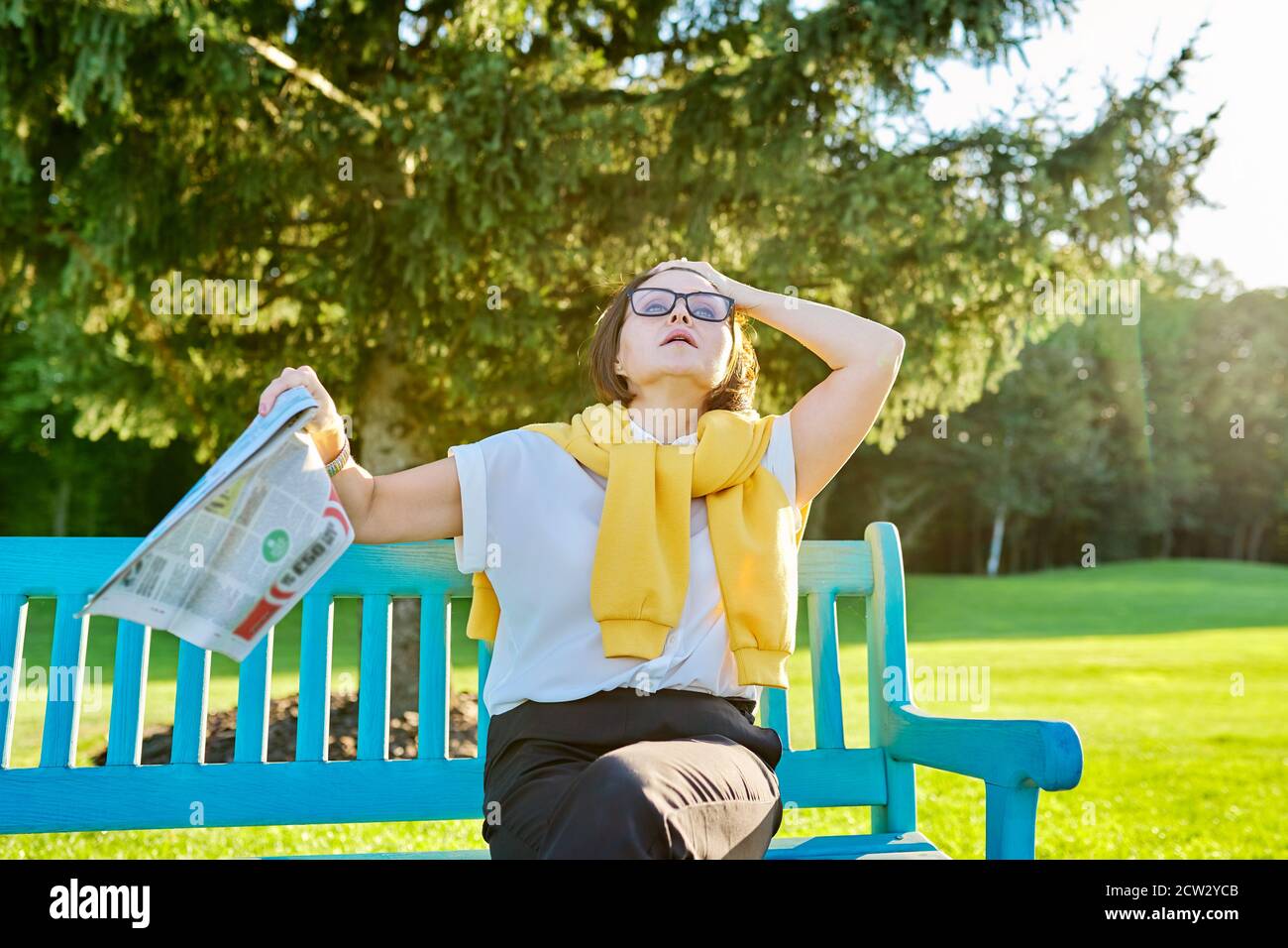 Symptoms of menopause in mature woman, female waves newspaper to cool off Stock Photo
